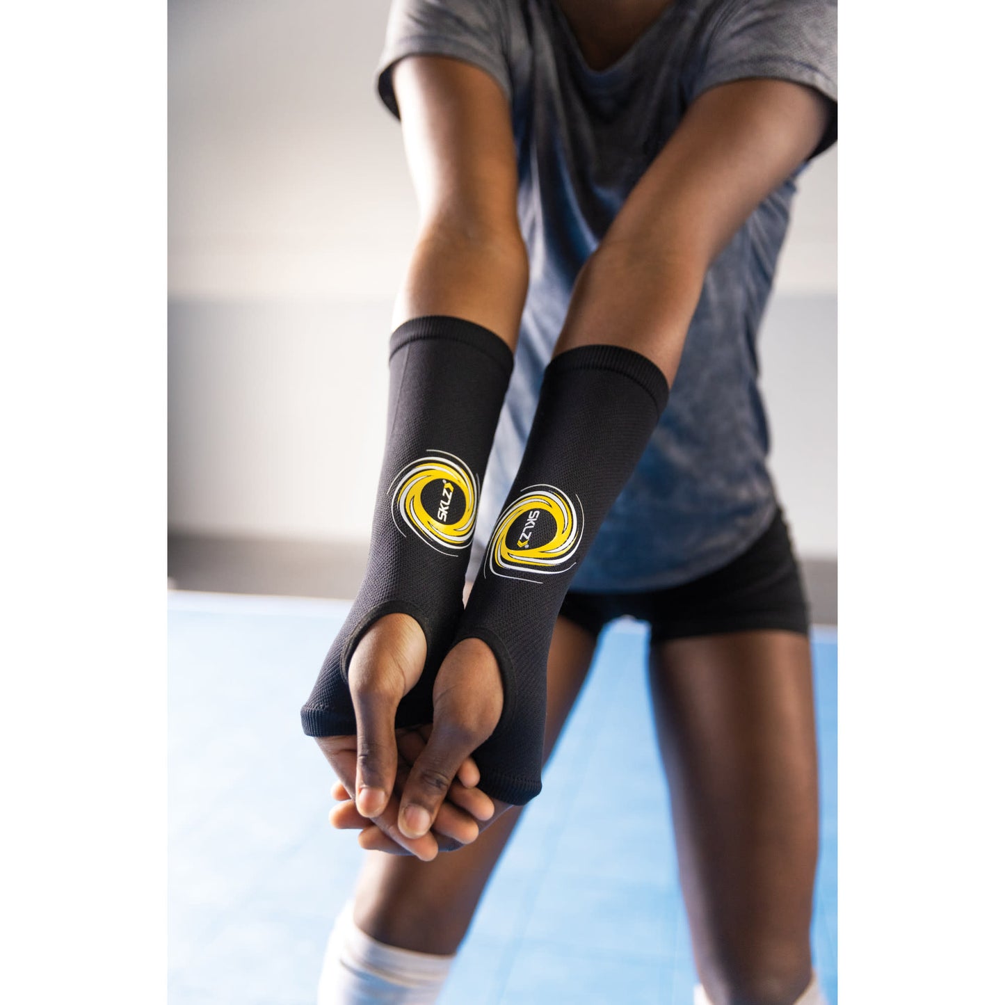 Person wearing fingerless gloves stretches arms in an indoor gym environment