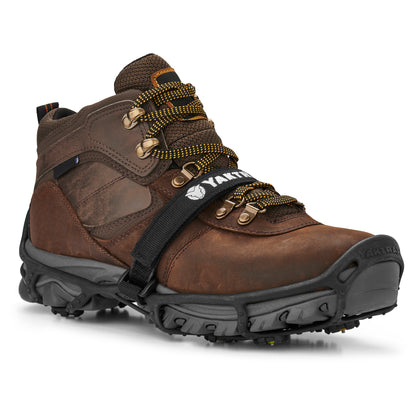 A brown hiking shoe is secured with a black strap in a retail display setting