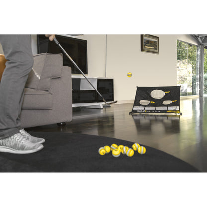 Person practicing golf chip shot indoors using a putter and a training net