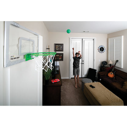 Boy throws ball towards a hoop in a living room with furniture and musical instruments