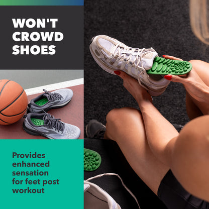 Hands insert green foot gel into white athletic shoes on a person's foot in a workout environment.