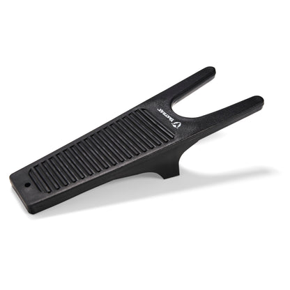 Boot jack resting on a white surface, featuring ribbed grip and U-shaped opening.