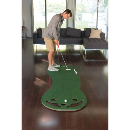 Man practicing golf indoors on a green mat in a living room
