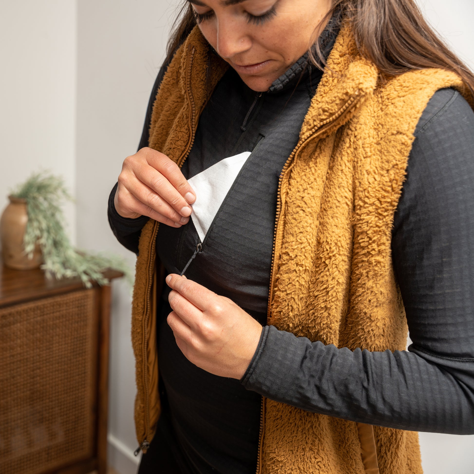 Woman unzips jacket to reveal a hidden pocket inside in indoor setting