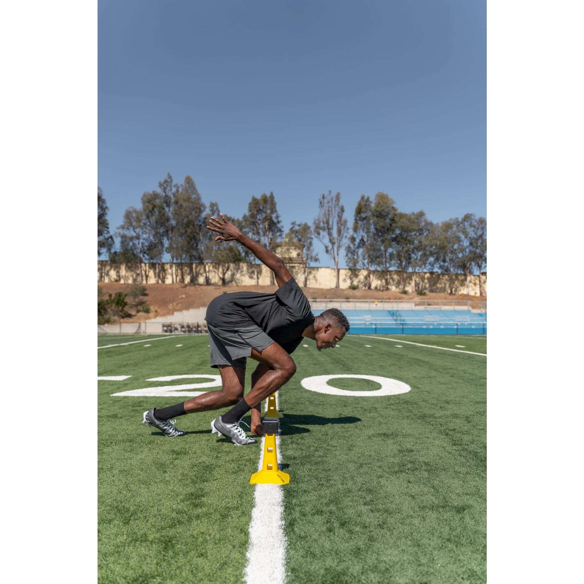 Athlete in starting stance on track ready to sprint during outdoor practice on a clear day
