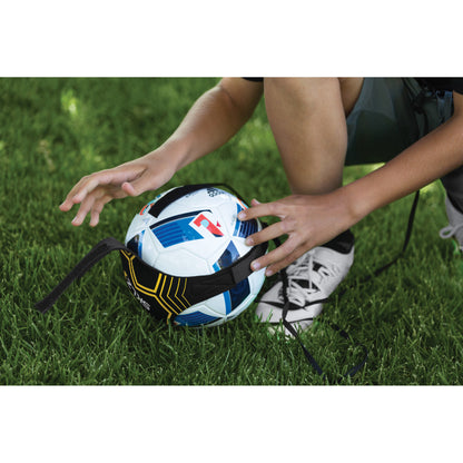 Person positions football on grass with a strap preparing for play